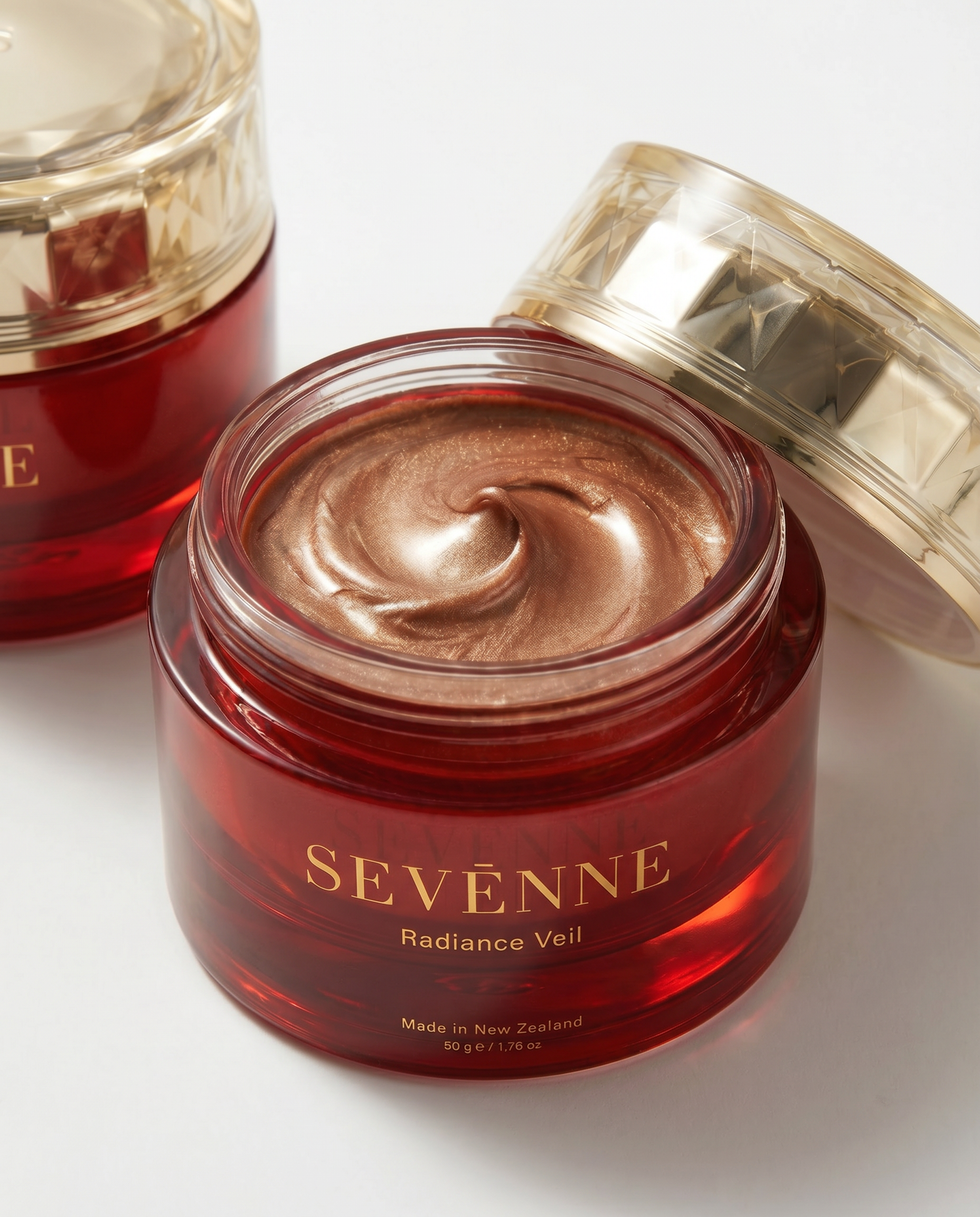 Red jar of Sevene Radiance Veil balm with a gold lid on a white background